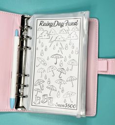 a planner with raindrops and umbrellas on it is open to show the inside pages