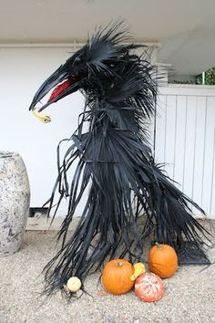 a bird made out of black feathers sitting next to pumpkins