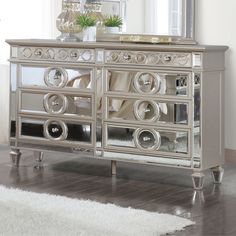 a silver mirrored cabinet with drawers and mirrors on the top, in front of a white rug