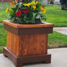 a wooden planter filled with flowers on top of a sidewalk