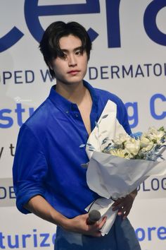 a man holding a bouquet of flowers in his right hand and wearing a blue shirt