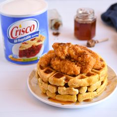 a stack of waffles sitting on top of a plate next to a jar of syrup