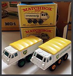 two toy trucks sitting next to each other in front of some boxes on a table