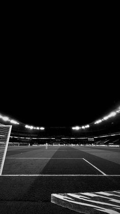 an empty soccer field at night with the lights on