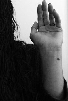 a woman's hand with a small star tattoo on her left wrist, in black and white