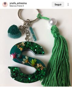 the letter s is made out of green sequins and has a tassel hanging from it