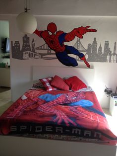 a bedroom with a spiderman wall decal on the wall and a bed in front of it