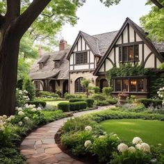 a large house surrounded by lush green trees and bushes with white flowers on the front