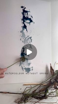 a person holding a flower in front of a wall with watercolour without brush