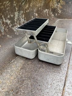 two metal trays sitting next to each other on the ground