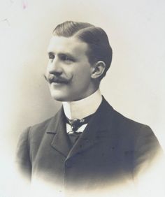 A man with a stylish handlebar moustache poses for a photo in Paris in the early 1900s. He has his hair slicked back with a side part and wears an elegant suit with a tie. Edwardian Photos, Edwardian Men, Men Suit Fashion, Hedda Gabler, Historical Hairstyles, 1920s Mens Fashion, Shirt Collars, Hairstyle Men, Military Dresses