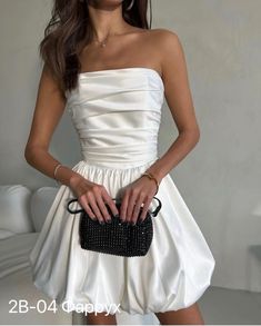 a woman in a white dress holding a black purse