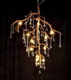 a chandelier with lights hanging from it's branches on a dark background