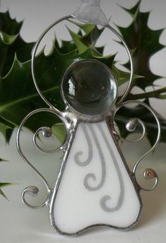 a glass angel ornament sitting on top of a table next to a green plant