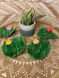 three green leaf shaped cookies sitting on top of a wooden table next to a potted plant