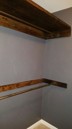 the corner of a room with two wooden shelves on one wall and a toilet in the other