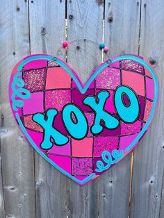 a pink and blue heart shaped sign with the word xoxo painted on it