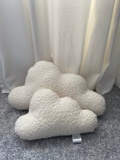 a white cloud pillow sitting on the floor next to a curtain