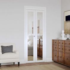 a white chair sitting in front of a mirror on top of a wall next to a dresser