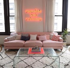 a living room filled with furniture and a neon sign on the wall above it's windows