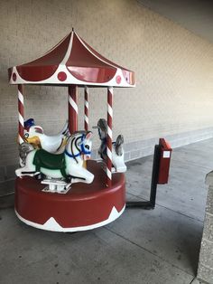 a merry go round with two horses on it's sides and a red roof