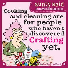 an older woman with pink hair sitting at a table in front of a sign that says cooking and cleaning are for people who haven't discovered crafting yet