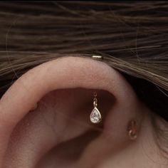 a woman's ear with a single diamond in it