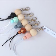 several wooden beaded keychains are lined up on a white surface with a name tag