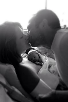 a man kissing a woman on the cheek while she sleeps with her baby in bed