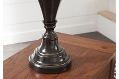 a table with a lamp on top of it in a room that has white walls and wood flooring