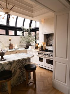 a kitchen with marble counter tops and stools next to an island in the middle