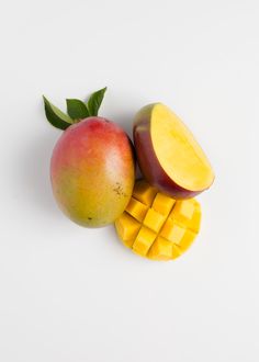 an apple, mango and piece of cheese on a white surface