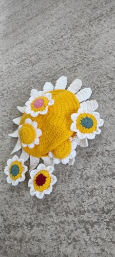 a crocheted yellow and white flower laying on the ground