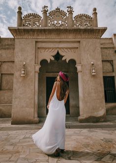 a woman standing in front of a building with a pink bandana on her head