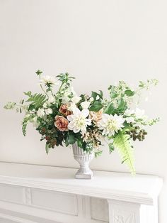 a vase filled with lots of flowers on top of a white table next to a window