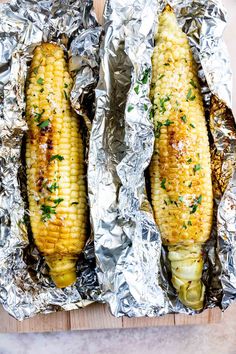 two grilled corn on the cob in aluminum foil