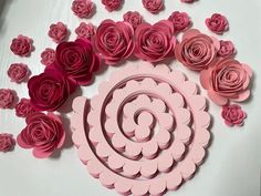 pink paper flowers arranged on top of a white table with cut out circles and petals