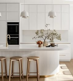 a kitchen with three stools in front of an island and two lights above it