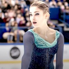 a female figure skating on an ice rink in front of a large group of people