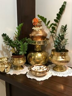 a table topped with lots of gold vases filled with plants and potted plants