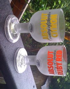 two empty wine glasses sitting on top of a wooden table next to trees and bushes