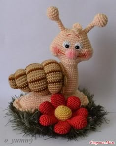 a crocheted snail sitting on top of a flower