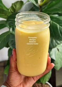 a person holding up a mason jar filled with orange juice and labeled the different ingredients