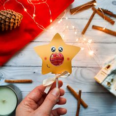 a hand holding a star shaped lollipop in front of some cinnamon sticks and christmas lights