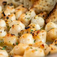 scallops and bread in a white bowl with herbs on top, ready to be eaten