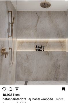 a bathroom with marble walls and flooring, shower head, soap dispensers on the wall