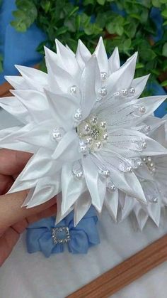 a white flower with pearls on it being held by someone's hand