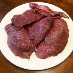 three pieces of raw meat on a white plate