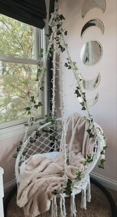 a white hanging chair in front of a window with plants growing on the seat and around it