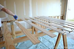 a man is painting the walls in his house with white paint and wood planks